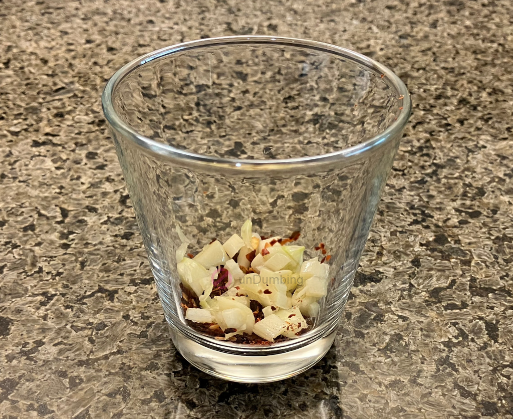 Chopped garlic and crushed red pepper in a shot glass