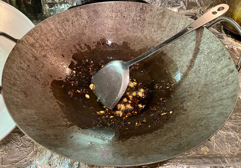 Chopped garlic and crushed red pepper added to the wok with oil