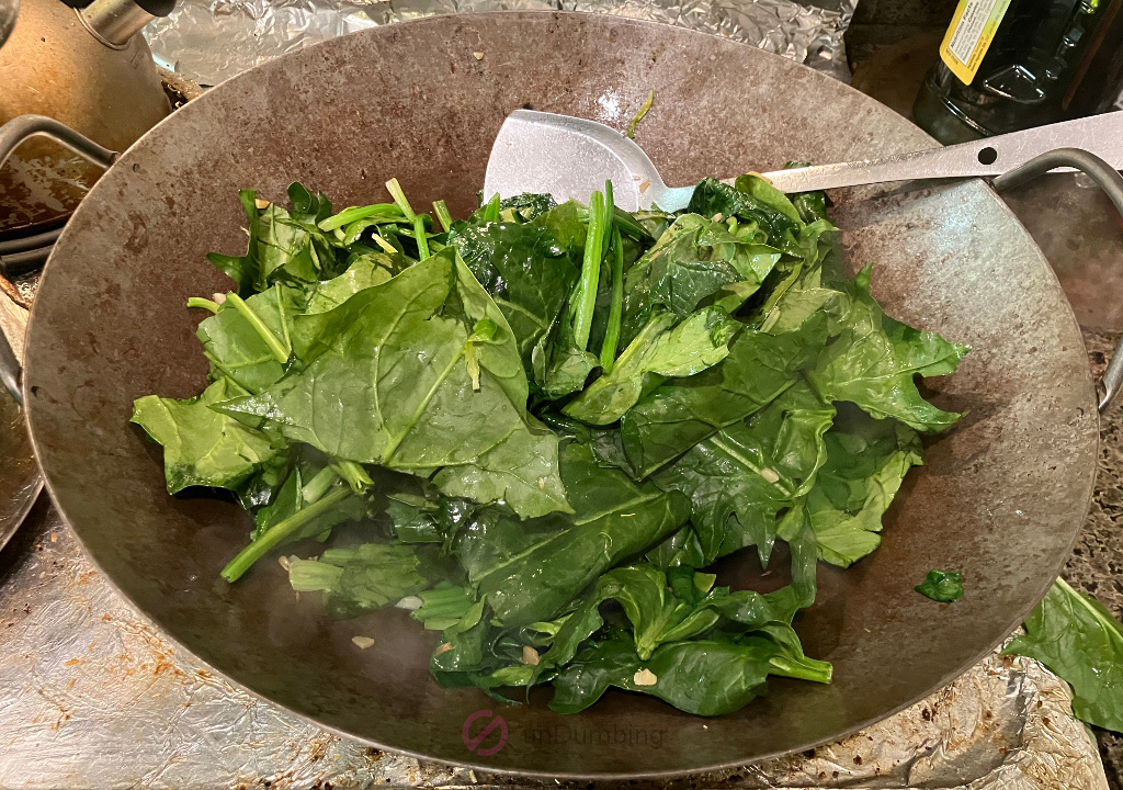 Spinach leaves cooking in a wok