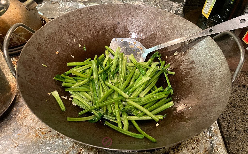 Spinach stems cooking in a wok