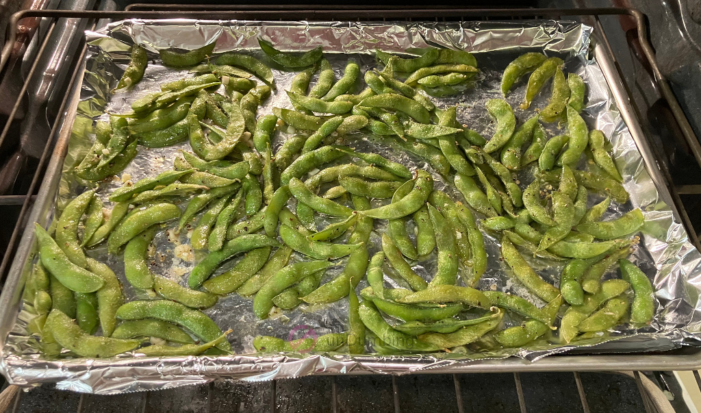 Edamame stirred halfway on a baking sheet