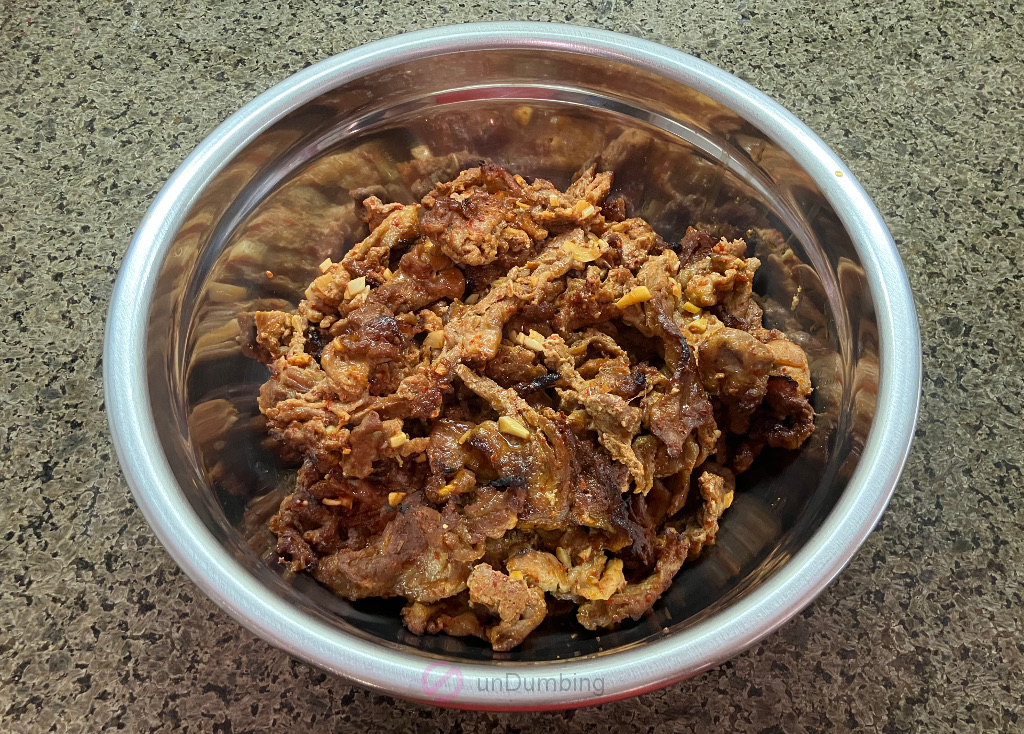 Baked Korean spicy pork in a stainless steel bowl